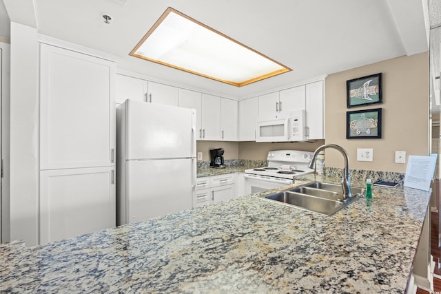 kitchen with sink, light stone counters, kitchen peninsula, white appliances, and white cabinets