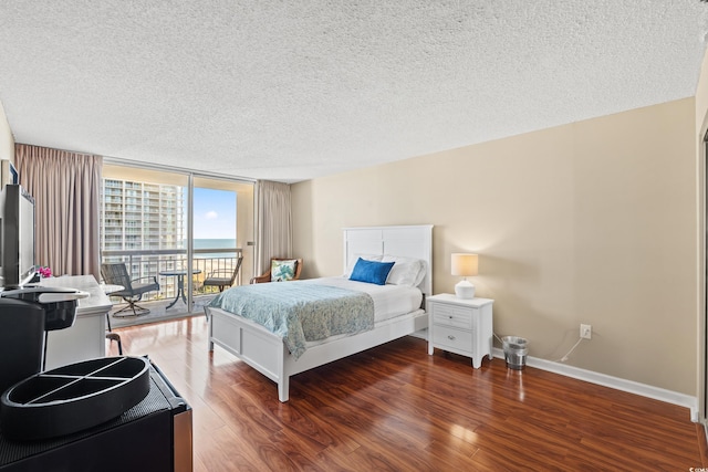 bedroom with floor to ceiling windows, dark hardwood / wood-style flooring, a textured ceiling, and access to outside