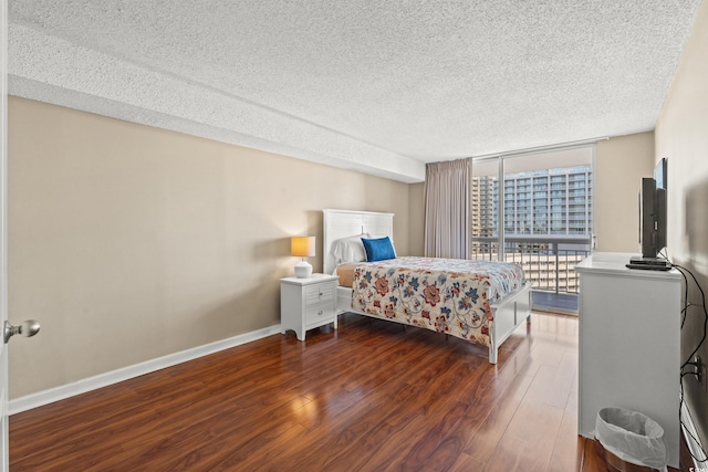 bedroom with a textured ceiling, access to exterior, dark hardwood / wood-style floors, and a wall of windows