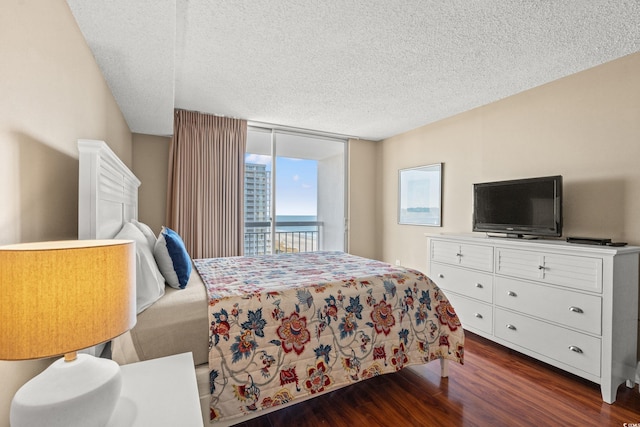 bedroom with a textured ceiling, dark wood-type flooring, and access to outside