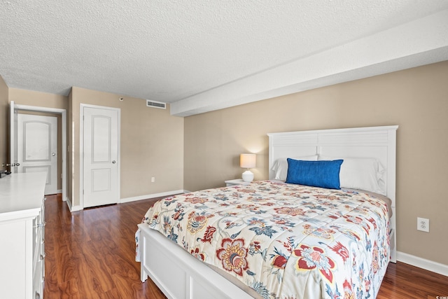 bedroom featuring dark hardwood / wood-style flooring and a textured ceiling