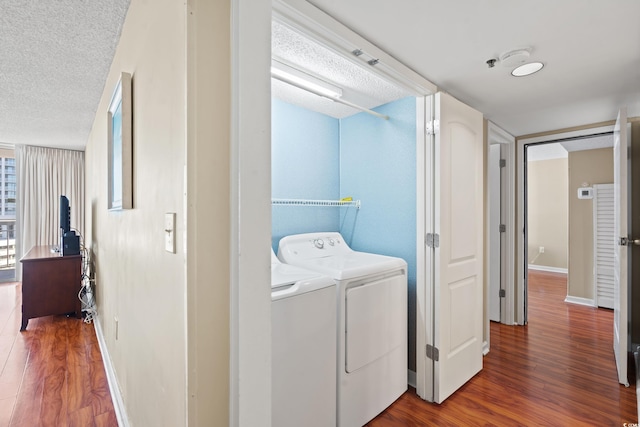 clothes washing area featuring washing machine and dryer, hardwood / wood-style floors, and a textured ceiling