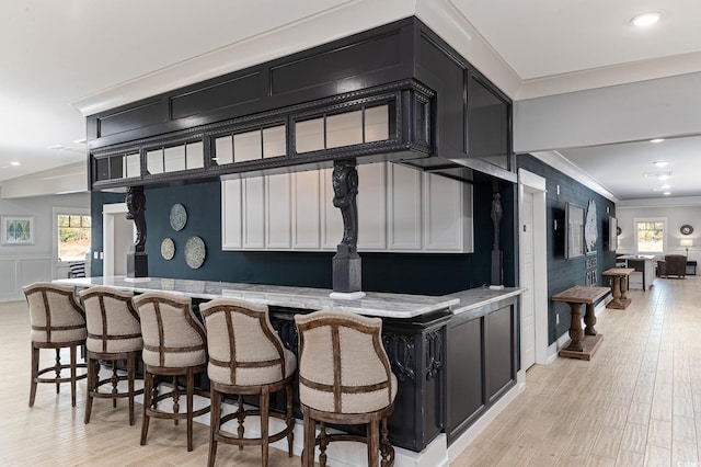 bar featuring white cabinets, plenty of natural light, crown molding, and light hardwood / wood-style flooring