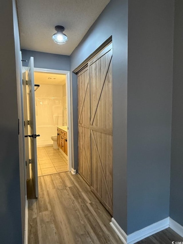 hall with a textured ceiling and light wood-type flooring