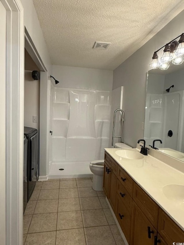 bathroom featuring washing machine and clothes dryer, tile patterned floors, a textured ceiling, and toilet