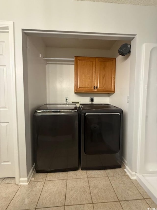 laundry area with washer and clothes dryer, light tile patterned flooring, and cabinets