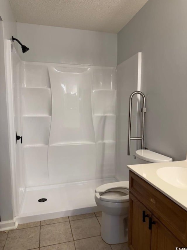 bathroom with vanity, a textured ceiling, a shower, tile patterned flooring, and toilet