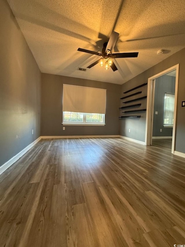 unfurnished living room with ceiling fan, dark hardwood / wood-style flooring, and a textured ceiling