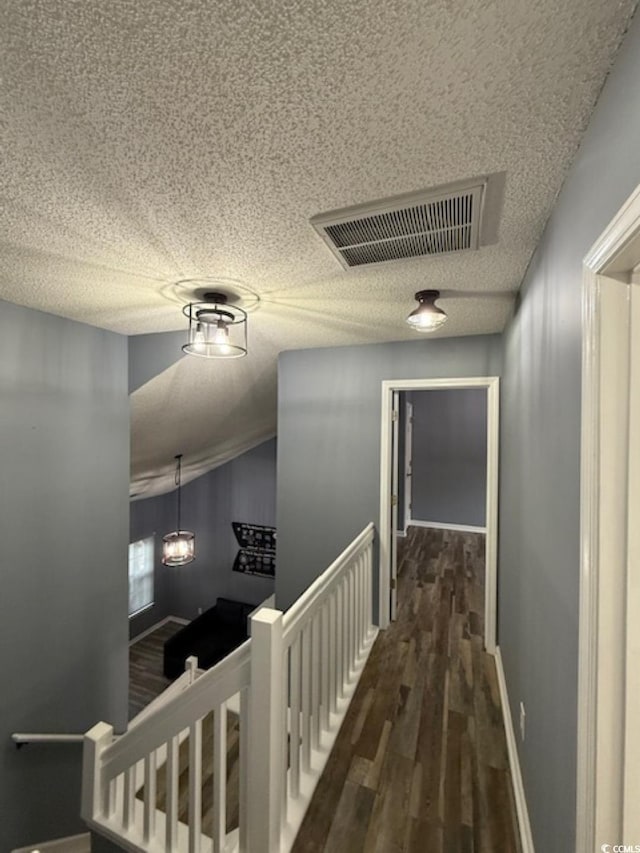 hall featuring a textured ceiling and dark wood-type flooring