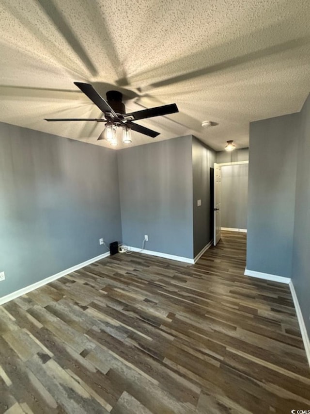 empty room featuring dark hardwood / wood-style floors, ceiling fan, and a textured ceiling