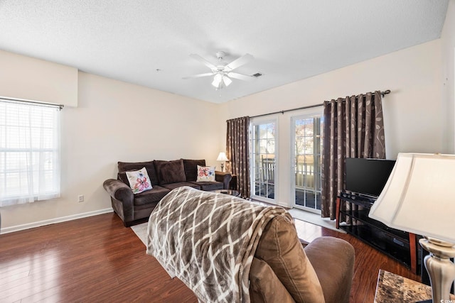 living room featuring a textured ceiling, ceiling fan, and dark wood-type flooring