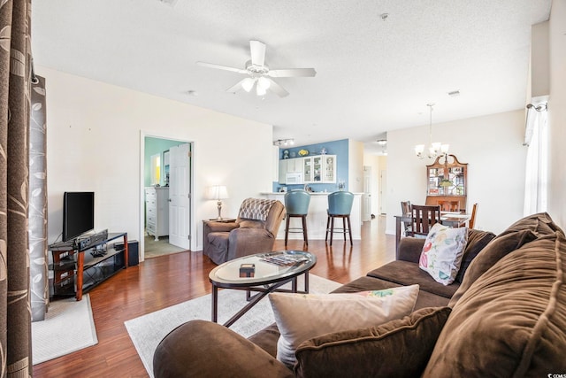 living room featuring a textured ceiling, dark wood-type flooring, and ceiling fan with notable chandelier