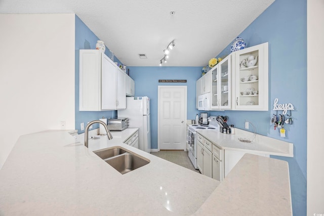 kitchen featuring white cabinets, a textured ceiling, white appliances, and sink