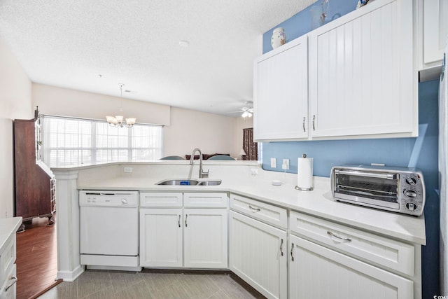 kitchen with pendant lighting, white dishwasher, kitchen peninsula, sink, and white cabinetry