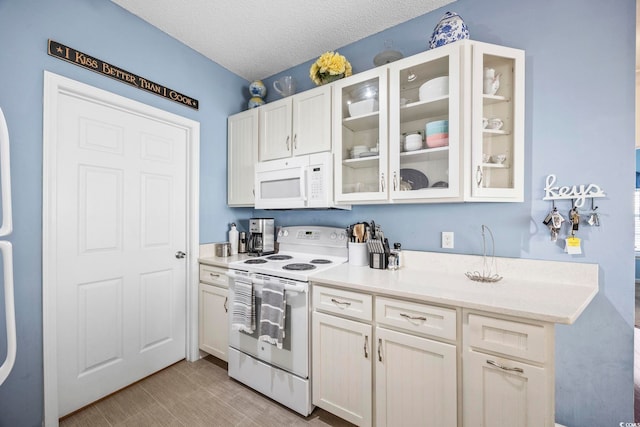 kitchen featuring white cabinets, white appliances, and a textured ceiling