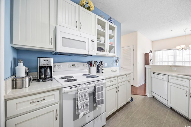 kitchen with white appliances, an inviting chandelier, hanging light fixtures, a textured ceiling, and white cabinetry