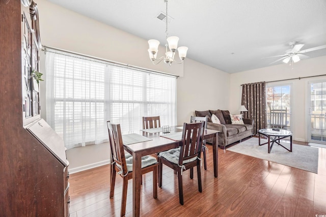 dining area featuring wood-type flooring and ceiling fan with notable chandelier