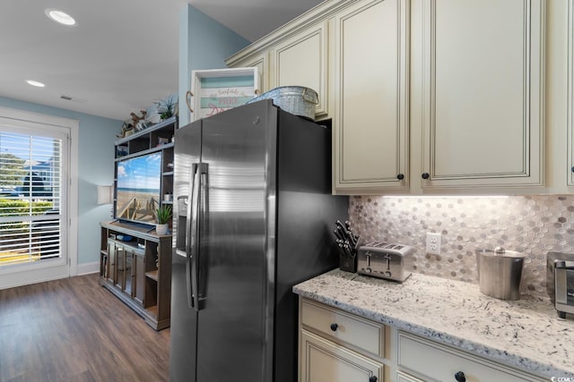 kitchen featuring light stone counters, backsplash, stainless steel fridge, cream cabinets, and hardwood / wood-style floors