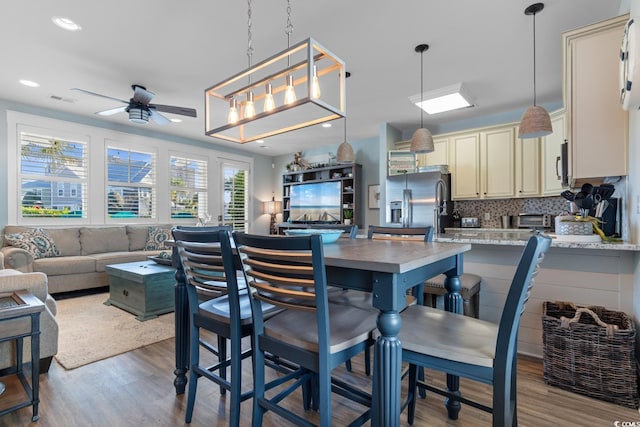 kitchen with ceiling fan, stainless steel appliances, light stone counters, backsplash, and light wood-type flooring