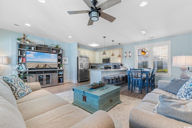 living room featuring ceiling fan and light hardwood / wood-style flooring