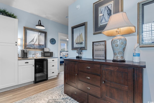 kitchen with white cabinets, plenty of natural light, wine cooler, and light hardwood / wood-style flooring