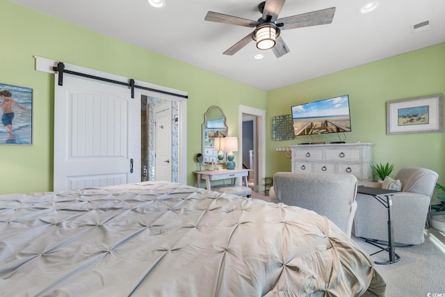 bedroom with a barn door, ceiling fan, and carpet