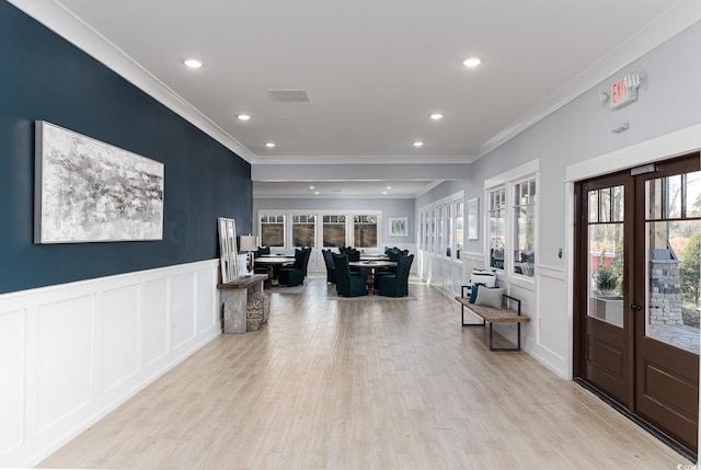 interior space with ornamental molding, french doors, a wealth of natural light, and light hardwood / wood-style flooring