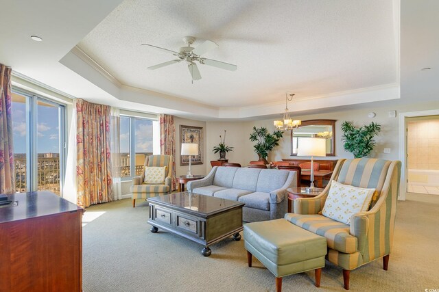 carpeted living room with ceiling fan with notable chandelier, a textured ceiling, and a tray ceiling