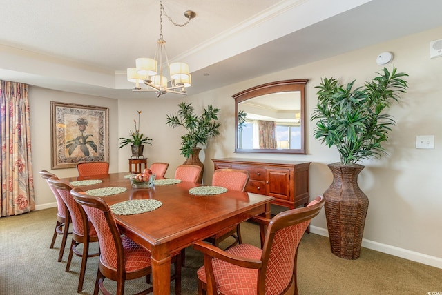 carpeted dining area with a raised ceiling, an inviting chandelier, and ornamental molding