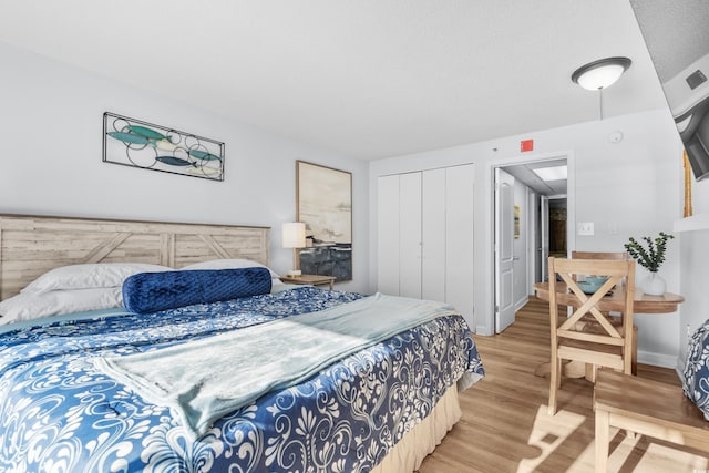 bedroom featuring a textured ceiling, light hardwood / wood-style floors, and a closet