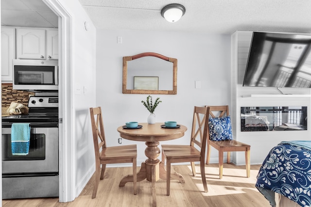 dining space with light wood-type flooring and a textured ceiling