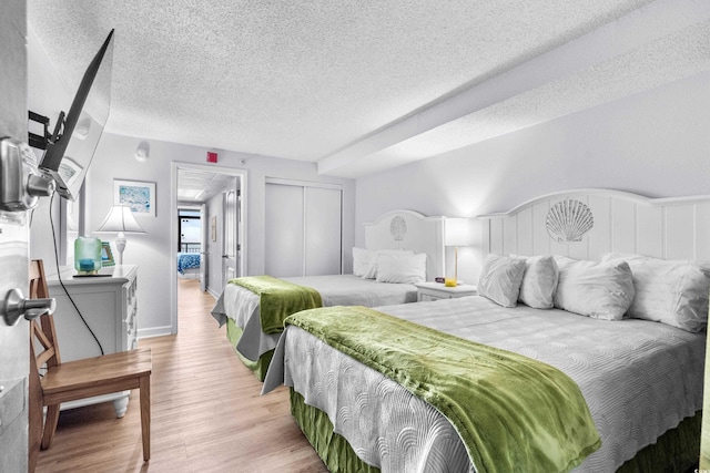 bedroom featuring a closet, a textured ceiling, and light wood-type flooring