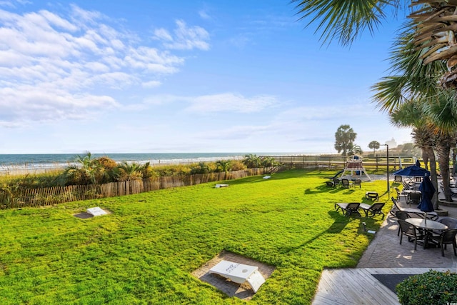 view of yard with a playground, a water view, and a beach view