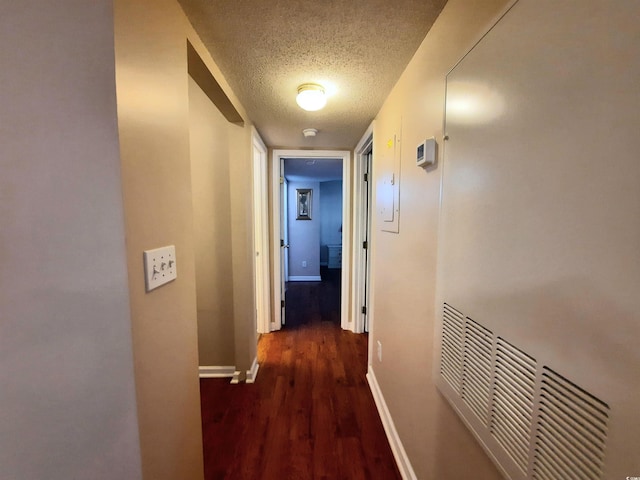 corridor with dark hardwood / wood-style flooring and a textured ceiling