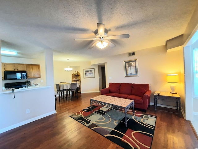 living room featuring dark hardwood / wood-style flooring, ceiling fan with notable chandelier, and a textured ceiling