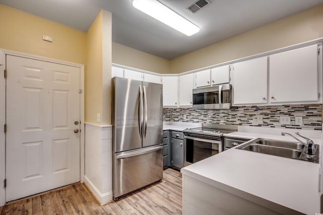 1286 River Oaks Dr Unit 8-M, Myrtle Beach, SC 29579 - kitchen with appliances with stainless steel finishes, light wood-style floors, decorative backsplash, white cabinets, and light countertops