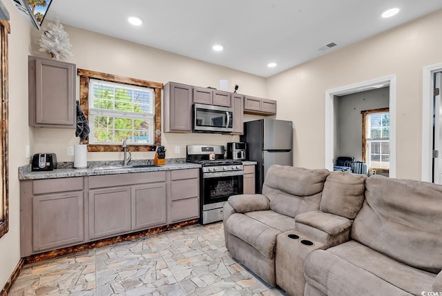 kitchen featuring gray cabinetry, light stone countertops, sink, and appliances with stainless steel finishes