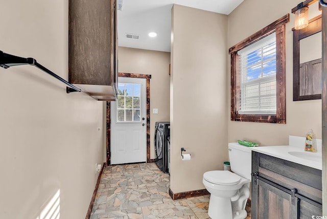 bathroom with washer and dryer, vanity, toilet, and plenty of natural light