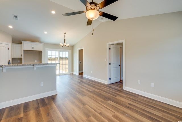 kitchen featuring light stone counters, dark hardwood / wood-style flooring, white cabinets, and lofted ceiling