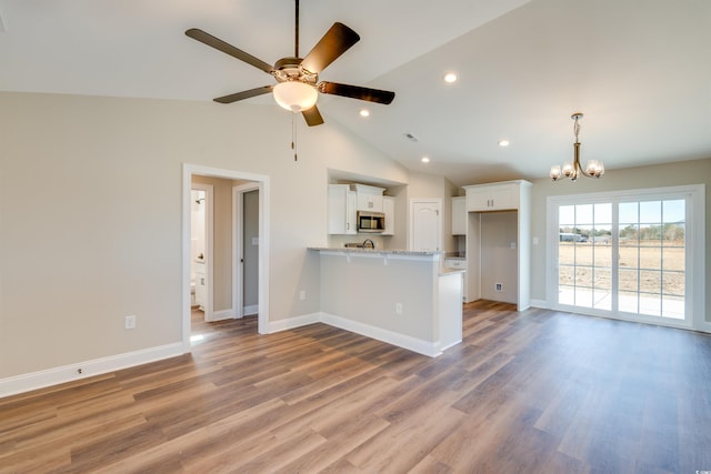 kitchen featuring white cabinetry, light stone countertops, kitchen peninsula, ceiling fan with notable chandelier, and hardwood / wood-style flooring