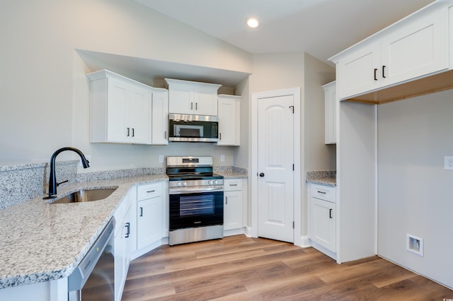 kitchen featuring white cabinetry, sink, stainless steel appliances, light hardwood / wood-style flooring, and vaulted ceiling