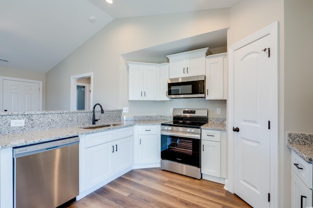 kitchen with white cabinets, sink, light hardwood / wood-style flooring, vaulted ceiling, and appliances with stainless steel finishes