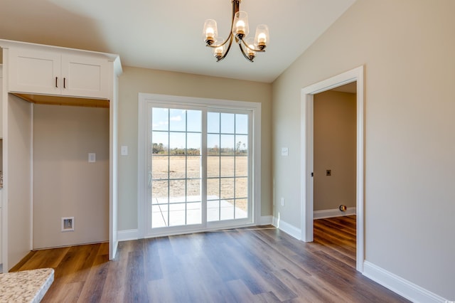 doorway to outside featuring hardwood / wood-style floors, vaulted ceiling, and a chandelier