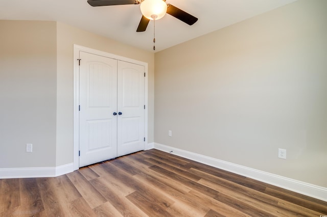 unfurnished bedroom featuring hardwood / wood-style flooring, ceiling fan, and a closet