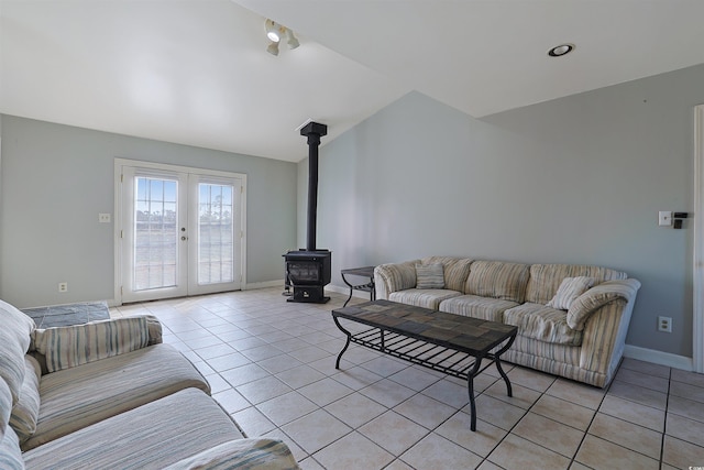 living room with french doors, vaulted ceiling, a wood stove, and light tile patterned flooring