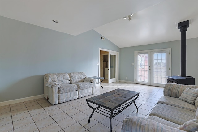 living room featuring a wood stove, french doors, light tile patterned flooring, and lofted ceiling