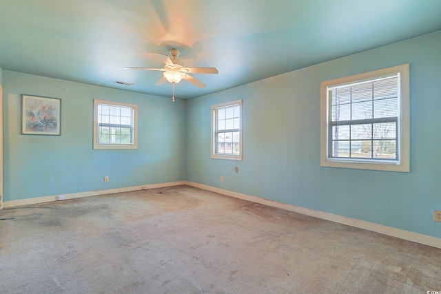 empty room featuring a wealth of natural light, ceiling fan, and light carpet