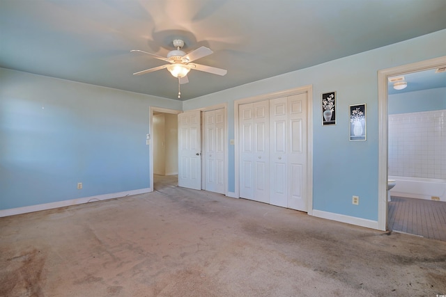 unfurnished bedroom with carpet, connected bathroom, two closets, and ceiling fan