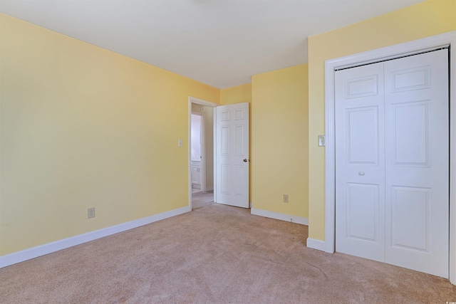 unfurnished bedroom featuring light carpet and a closet