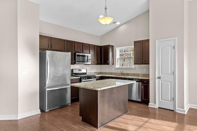 kitchen with sink, a center island, stainless steel appliances, pendant lighting, and wood-type flooring